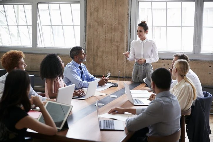 A facilitator leads a collaborative discussion around a shared table.