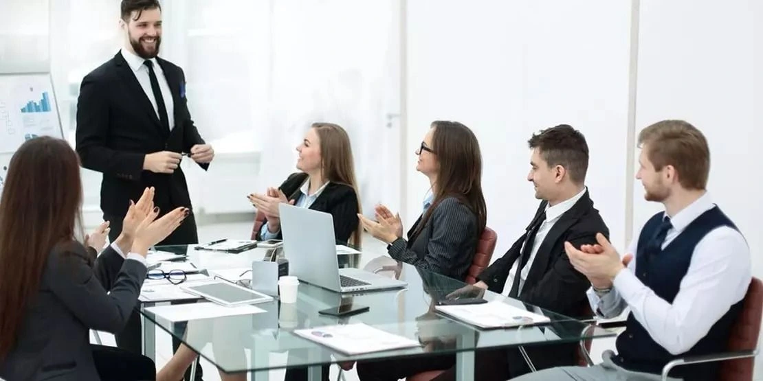 A presenter addresses colleagues in a bright professional environment.