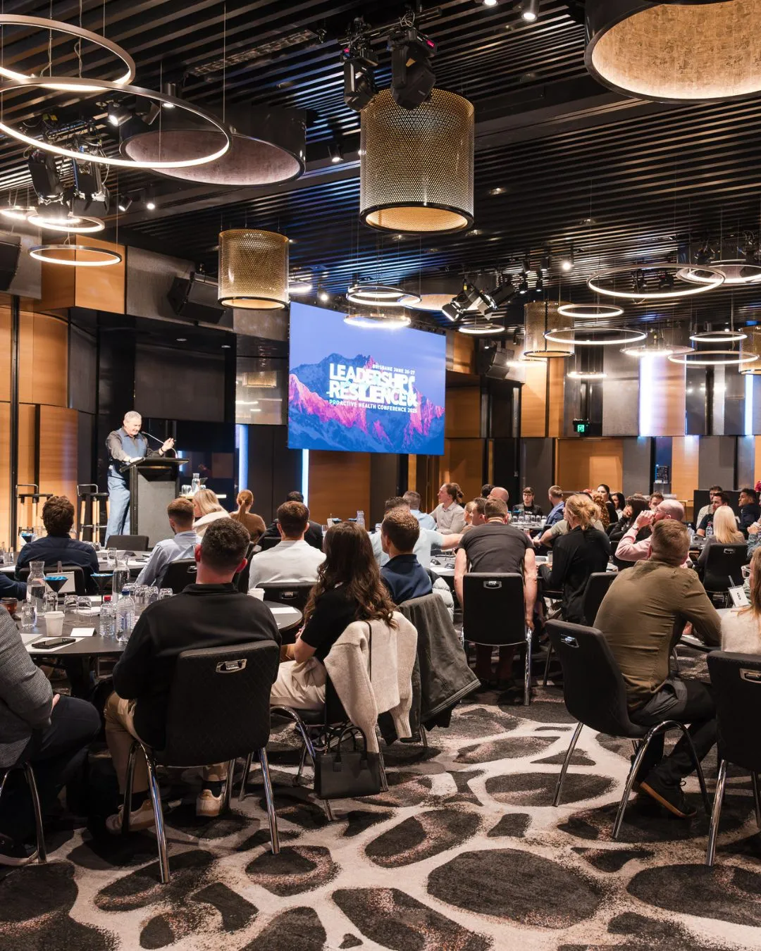 A speaker addresses participants in a professional conference setting.